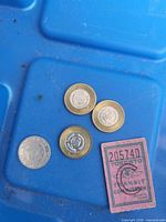 Four TTC tokens and pink ticket on blue background