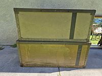 Two stacked olive drab military shipping cases showing overall form and wear