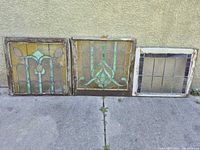 Three stained glass windows standing on ground against wall