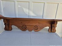 Front angled view showing carved apron and side supports of wood shelf