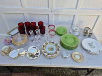 Overview of all items laid on table including charger, uranium plates, red tumblers, crystal stems, porcelain pieces