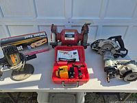 Group view of bench grinder, disc sander, cut-off tool in box, DeWalt tool in case, Porter-Cable circular saw