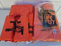 Stacked adult and child Kent life vests, one sealed in plastic