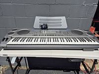 Front view of Casio WK-1630 keyboard on stand with music rest and power adapter