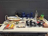 Overview of assorted items on folding table including faucets, glassware, finials, games