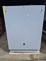 Front view of white GE dishwasher showing overall condition and dent top right