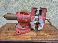 Side view of red bench vise on wood surface