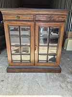 Front view showing drawers, glass-paneled doors, plinth base