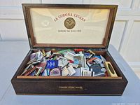 Closed wooden La Corona cigar box open to show interior branding and matchbooks inside