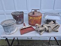 All items displayed on table including gasoline can, bucket, chimney cap, perforated pail, dustpan, straps