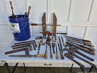 Overview of entire lot on table showing clamps, squares, drills, wrenches, screwdrivers, chisels and bucket of files