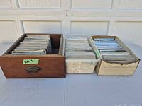 Three containers filled with postcards, wooden drawer at left