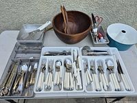 Overview of entire lot showing wooden bowl, flatware trays, utensil baskets, enamel bowl