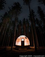 Illuminated geodesic dome in forest representing accommodation