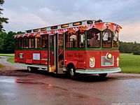 Exterior view of red Town Trolley vehicle at dusk with lights on