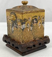 Front view showing painted figures and carved wood stand