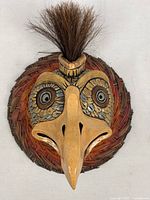 Front view of ceramic bird mask on woven fiber base showing overall design