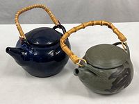 Both teapots side by side showing overall form, glaze colors, bamboo handles