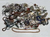 overview of large pile of assorted costume jewelry on white surface