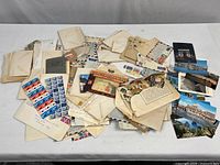 Overview of envelopes, stamps and postcard folder spread on table