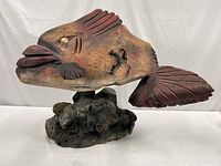 full view of fish sculpture on rock-like wooden base