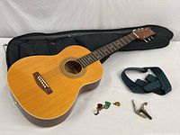 Full view of guitar with bag, strap, picks, capo