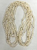 Full view of the long pearl strand laid out on fabric background