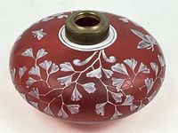 Side view of red glass lamp font showing enamel floral motif