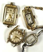 Group shot of all four wristwatches showing fronts and attached bands