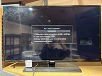 Front view of powered-on Samsung 40-inch TV on stand showing "No Cable Connected" screen