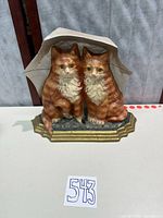 Front view of cast iron doorstop showing two kittens under umbrella