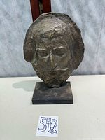 Front view of bronze-tone head sculpture on base