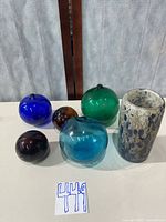 Group shot of four coloured glass balls and mottled glass cup