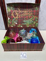 Open plaid "Season’s Greetings" box showing all eight ornaments
