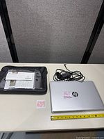 Laptop with power adapter, paperwork and briefcase overall view