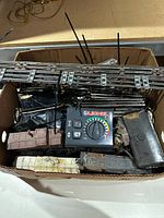 Box with Lionel controller, track sections, rolling stock