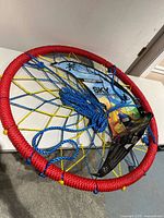 Overall view of 38-inch rope web swing showing red outer ring, blue net, yellow cords, and packaging card