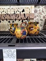 Three hand-painted earthenware vessels on shelf