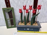 Planter with tulip flowers and green miniature screen door side by side with measuring tape for scale