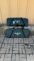 Two green Cam-O-Cot carry cases stacked against wall