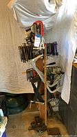 Full view of vertical stand loaded with assorted clamps, vise at base