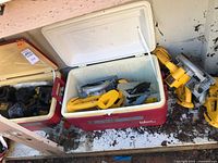 Two coolers containing assorted yellow DeWalt saws and black chargers