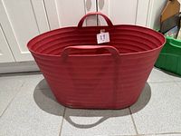 Full view of red plastic basket showing handles and ribbed design