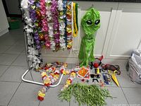 Overview of leis, hula skirt, inflatable alien, bags, masks and accessories on floor