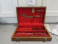 Closed wooden case opened showing red felt interior and utensils neatly arranged