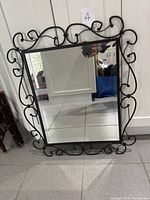 Front view of mirror showing wrought iron scroll frame