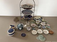 overview of entire lot on surface showing stand, plates, dishes, jars, trivet, votives