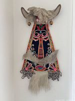 Full view of embroidered horned textile mask