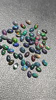 Group of multicolored black opal cabochons on textured background
