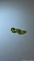 Two apple green peridot gemstones on neutral background